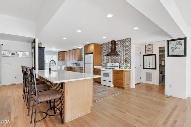 a large white kitchen with stainless steel appliances granite countertop a stove and a sink