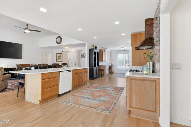 a kitchen with stainless steel appliances granite countertop a stove a sink dishwasher and a refrigerator with wooden floor