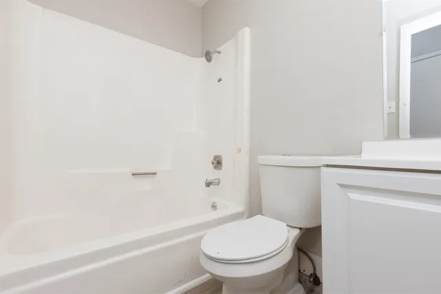 a white toilet sitting next to a bath tub