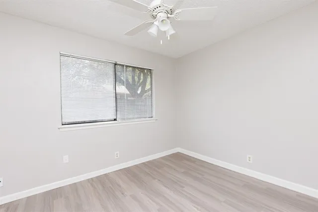 an empty room with a window and a fan