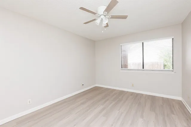 an empty room with a window and a ceiling fan