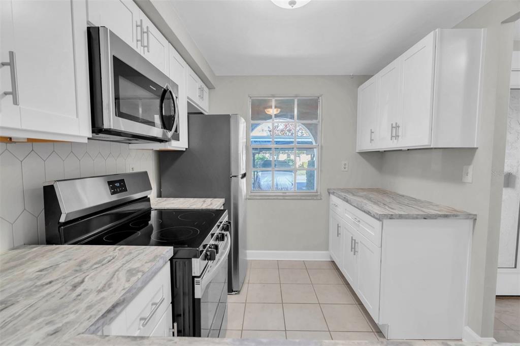 4343 Summersun Drive, Unit 4343 New Port Richey, FL 34652 - Photo 6 of 50 a kitchen with granite countertop a stove top oven microwave and cabinets