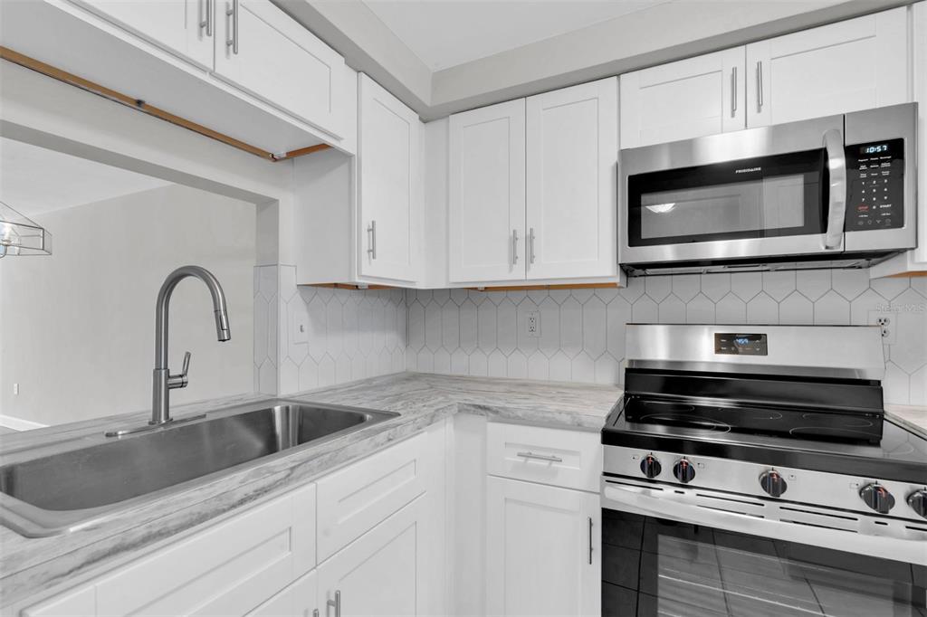 4343 Summersun Drive, Unit 4343 New Port Richey, FL 34652 - Photo 7 of 50 a kitchen with stainless steel appliances granite countertop white cabinets a microwave and a sink