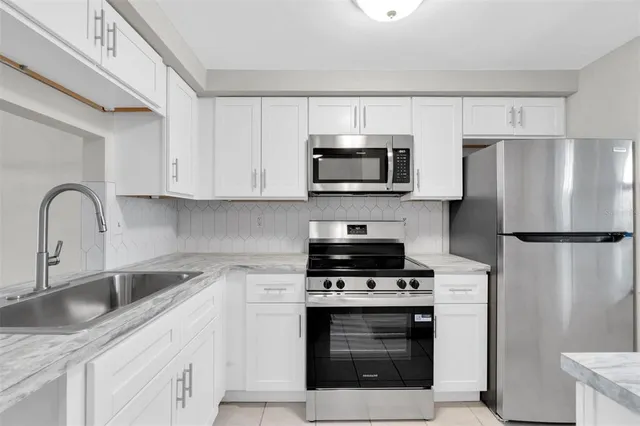 a kitchen with granite countertop white cabinets and white appliances