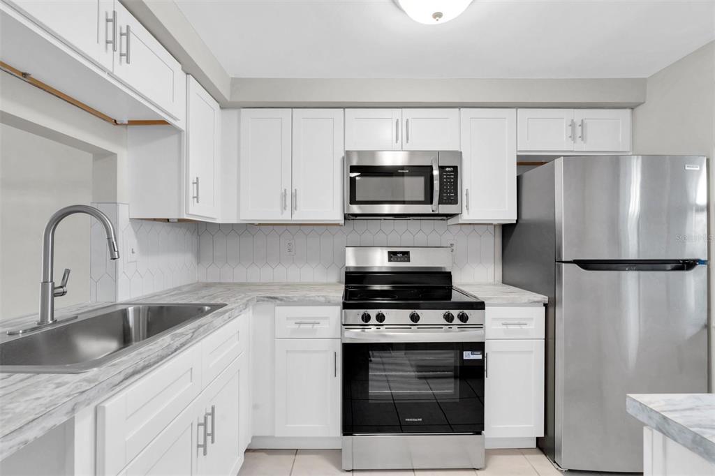 4343 Summersun Drive, Unit 4343 New Port Richey, FL 34652 - Photo 8 of 50 a kitchen with stainless steel appliances a stove a sink a refrigerator and cabinets