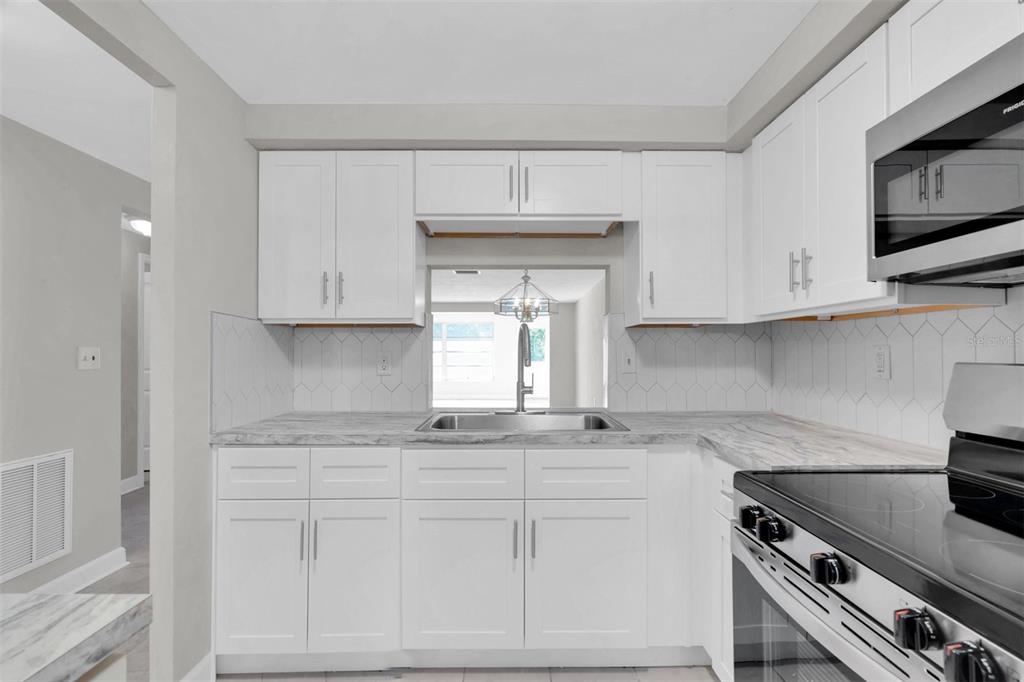 4343 Summersun Drive, Unit 4343 New Port Richey, FL 34652 - Photo 9 of 50 a kitchen with granite countertop white cabinets and white appliances
