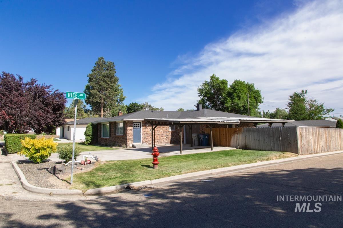 1404 Rochester Street Caldwell, ID 83605 - Photo 1 of 29 Brick residence featuring a covered carport, mature landscaping, a wooden privacy fence, and a corner lot