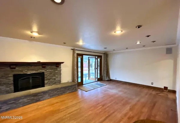 an empty room with wooden floor fireplace and windows