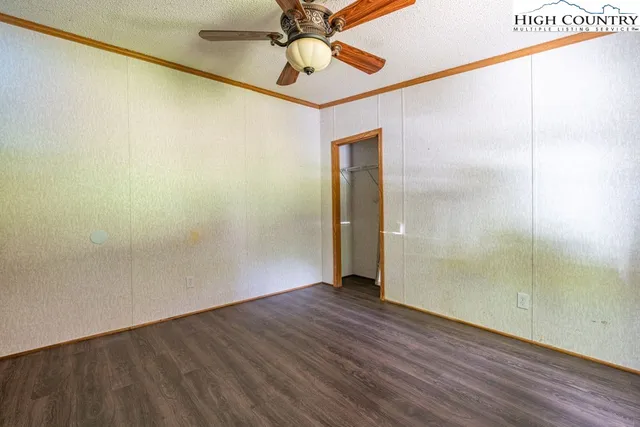 an empty room with wooden floor and fan