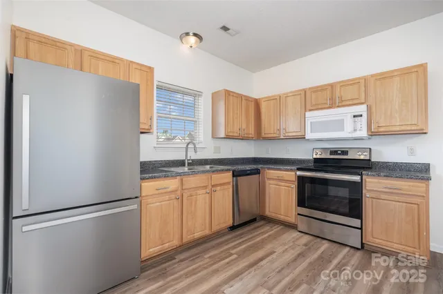 a kitchen with stainless steel appliances granite countertop a refrigerator sink and stove