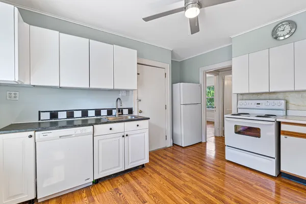 a kitchen with granite countertop white cabinets and white appliances