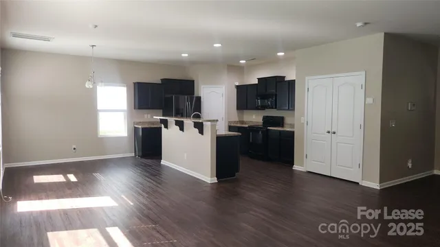 a view of a kitchen with refrigerator and wooden floor