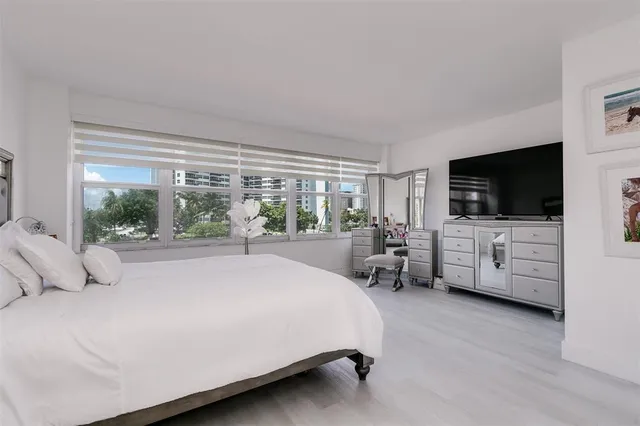 a bed room with a bed a television and a large window