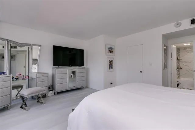 a bedroom with a bed and a flat tv screen on wall