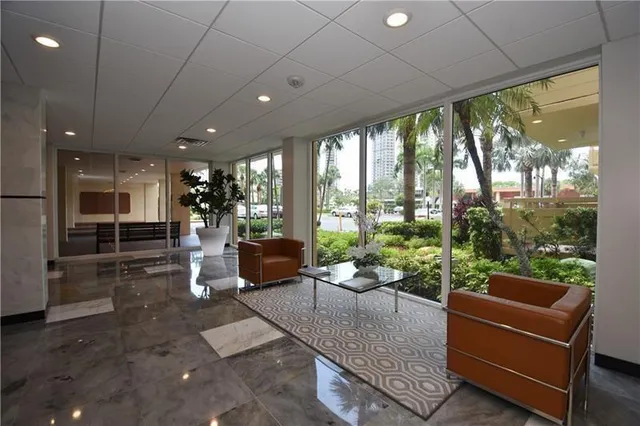 a living room with patio furniture and floor to ceiling windows