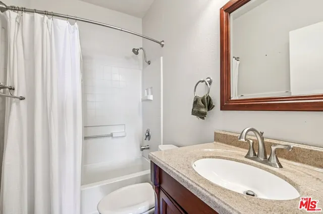 a bathroom with a granite countertop sink toilet and shower