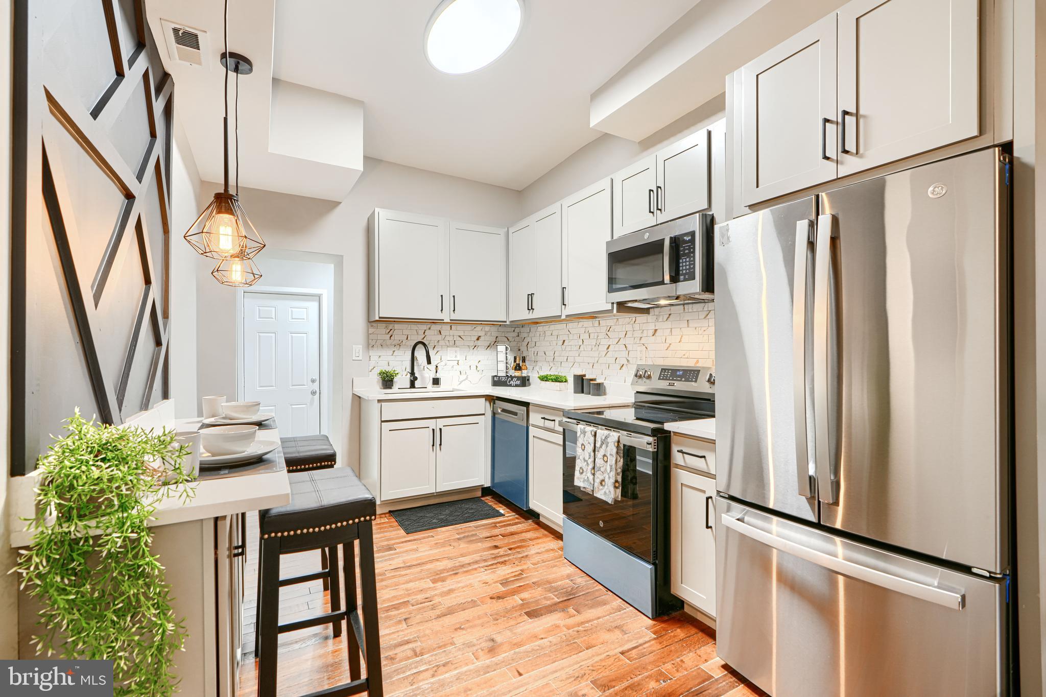 717 East Biddle Street Baltimore, MD 21202 - Photo 16 of 47 a kitchen with stainless steel appliances granite countertop a refrigerator a stove a sink dishwasher and a refrigerator with wooden floor