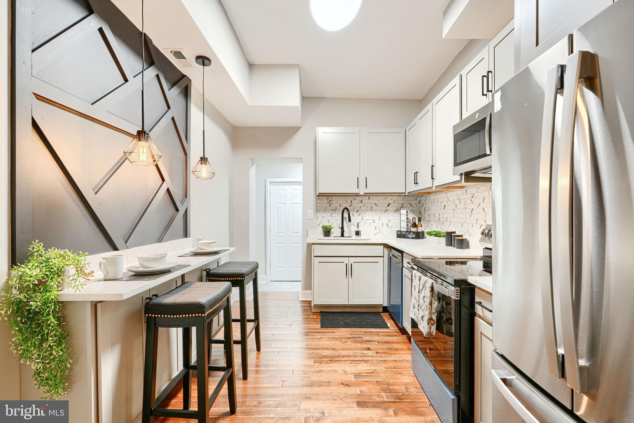 717 East Biddle Street Baltimore, MD 21202 - Photo 18 of 47 a kitchen with stainless steel appliances granite countertop a refrigerator a stove a sink and white cabinets with wooden floor