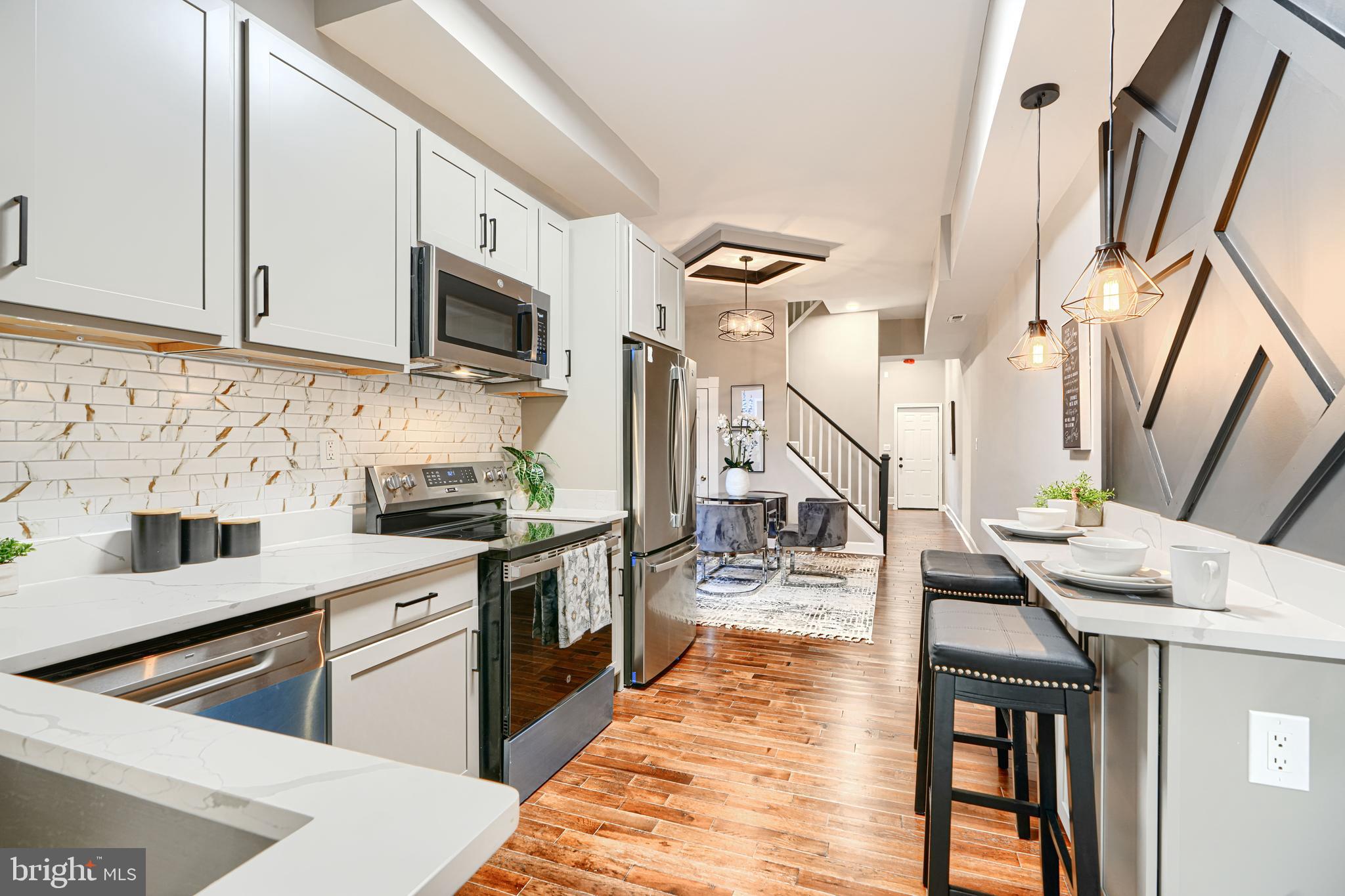 717 East Biddle Street Baltimore, MD 21202 - Photo 23 of 47 a kitchen with stainless steel appliances granite countertop a stove a sink dishwasher and white cabinets with wooden floor
