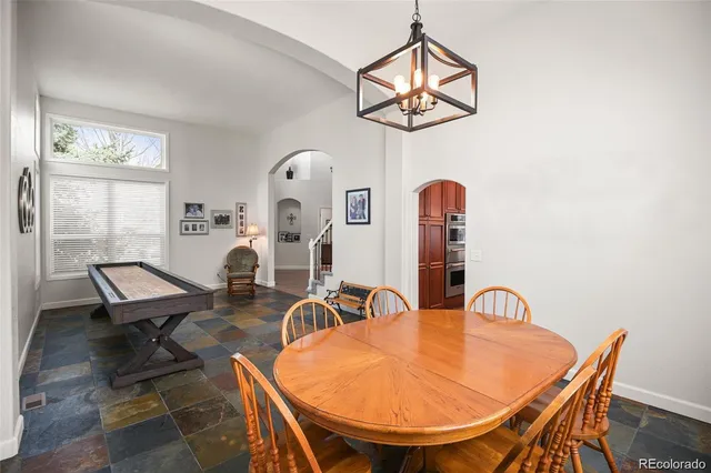 a dining room with wooden floor a chandelier a glass table and chairs