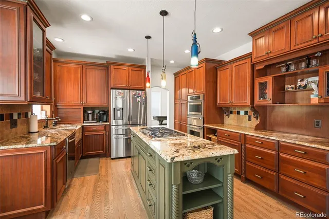 a kitchen with a stove a sink dishwasher a refrigerator and wooden cabinets with wooden floor