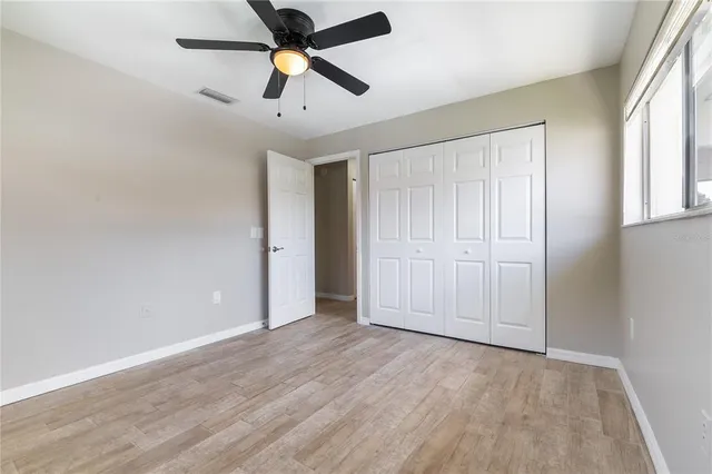 an empty room with wooden floor & closet area