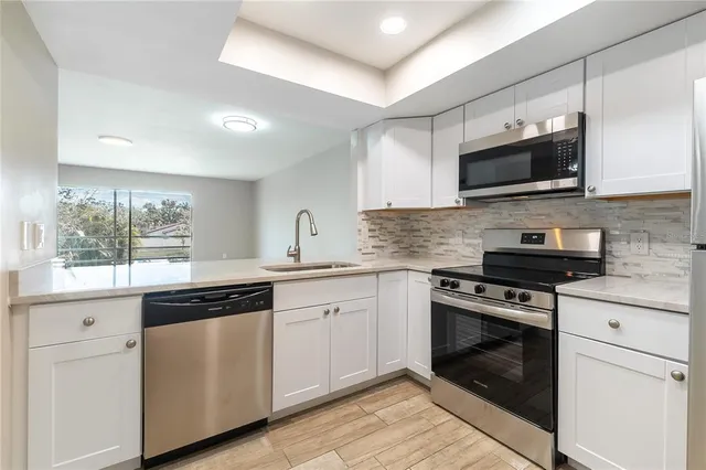 a kitchen with stainless steel appliances granite countertop grey cabinets a sink and a stove