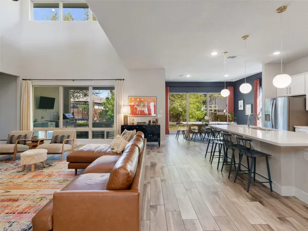 a living room with furniture a large window and wooden floor