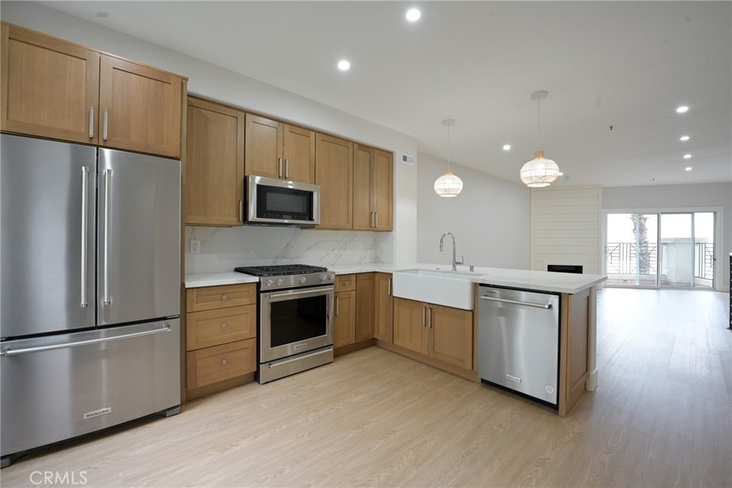 a kitchen with stainless steel appliances granite countertop a refrigerator a sink dishwasher a stove top oven and a refrigerator with wooden floor