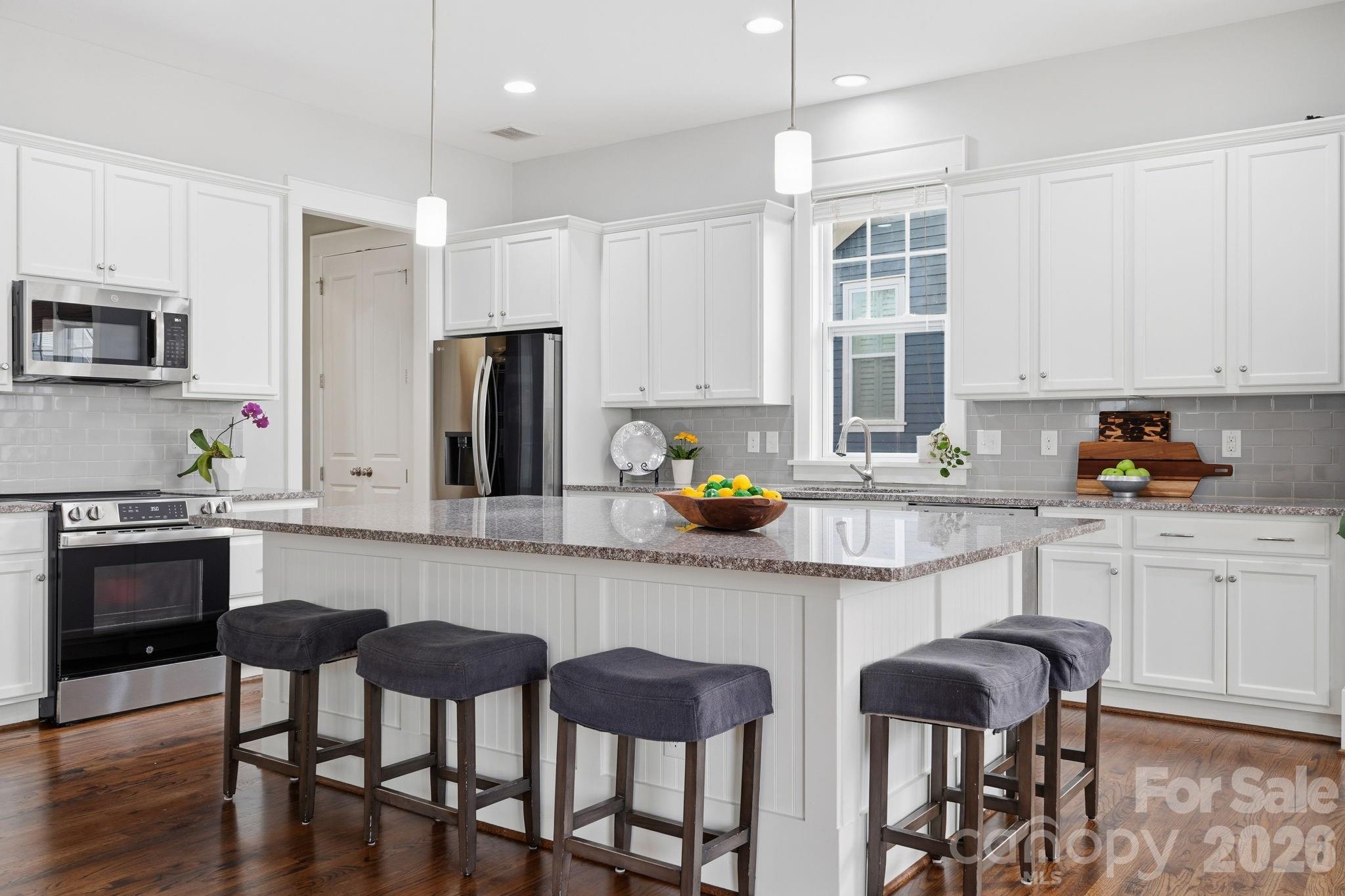 312 Mill Ridge Road Rock Hill, SC 29730 - Photo 12 of 42 a kitchen with stainless steel appliances granite countertop a stove a sink a microwave a dining table and chairs with wooden floor