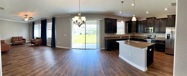 a kitchen with kitchen island granite countertop a sink a counter top space appliances and cabinets