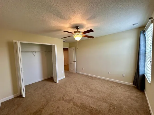 an empty room with closet and a ceiling fan