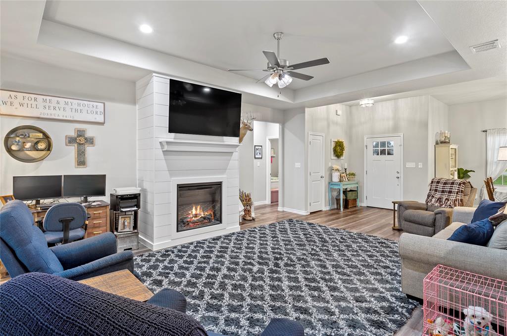 141 Walnut Street Paradise, TX 76073 - Photo 12 of 23 Living area featuring wood finished floors, a raised ceiling, a fireplace, a ceiling fan, and a desk