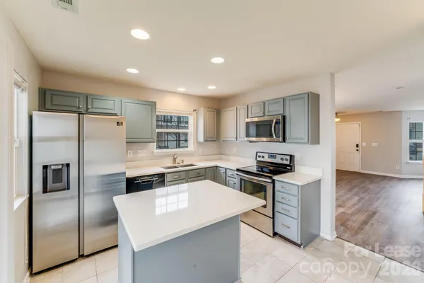 a kitchen with stainless steel appliances granite countertop a refrigerator a stove and a sink