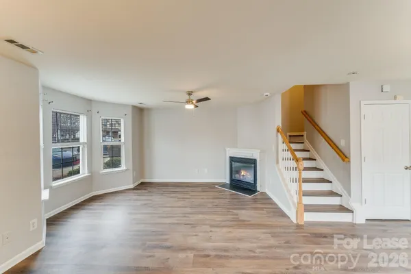 a view of an empty room with wooden floor and windows