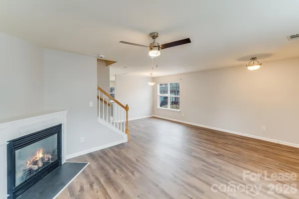 a view of an empty room with wooden floor fireplace and a window