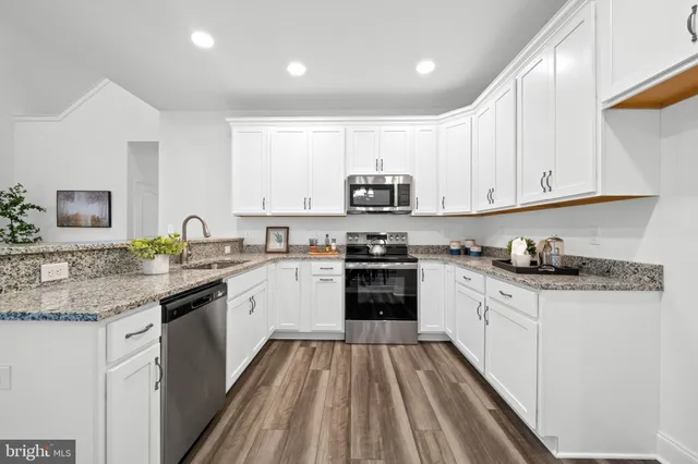a kitchen with granite countertop a sink stove and cabinets