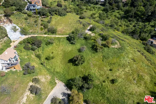 an aerial view of residential houses with outdoor space and trees