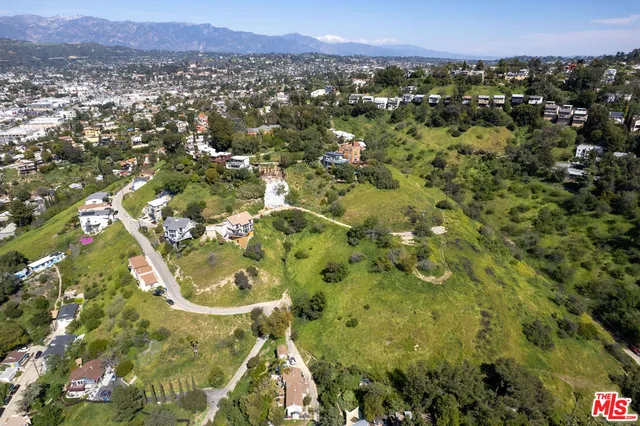 an aerial view of a residential houses with outdoor space and trees