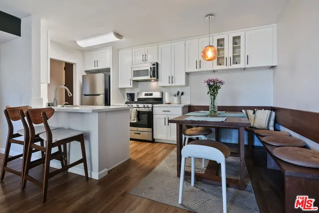 a kitchen with stainless steel appliances granite countertop a table chairs refrigerator and sink