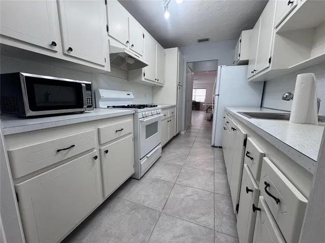 a kitchen with a sink stainless steel appliances and white cabinets