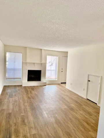 a view of empty room with wooden floor and fireplace