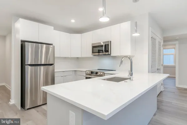 a kitchen that has a sink a refrigerator and a stove top oven