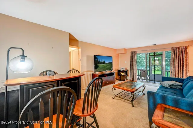 a living room with furniture a flat screen tv and floor to ceiling window