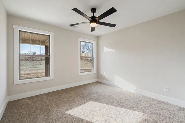 an empty room with windows and ceiling fan