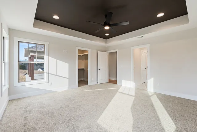 a view of an empty room with glass door and chandelier fan
