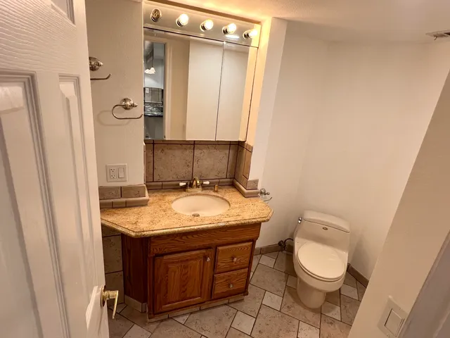 a bathroom with a granite countertop sink toilet and mirror