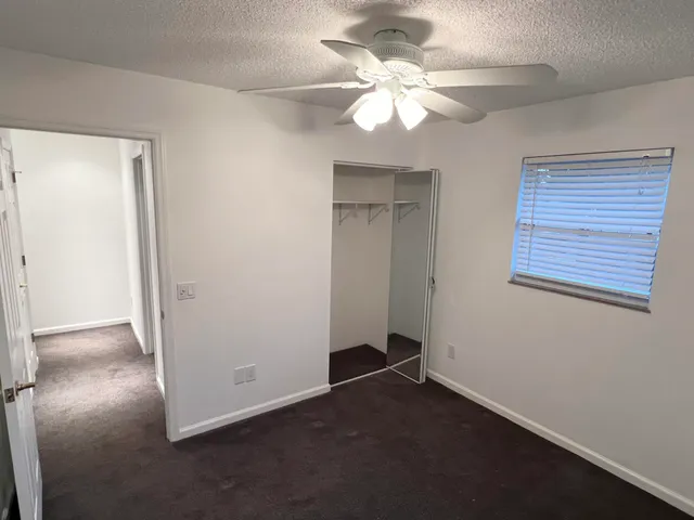 an empty room with a chandelier fan and windows