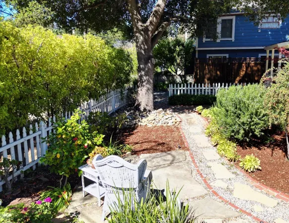 a view of a white house with wooden fence and a tree