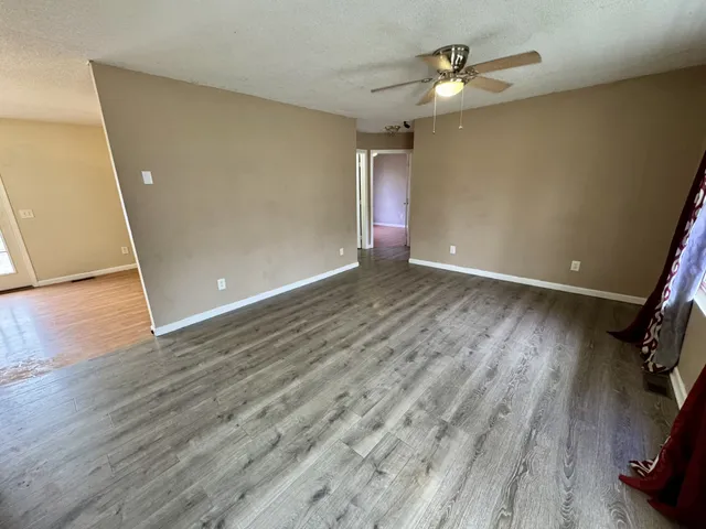 an empty room with wooden floor and windows